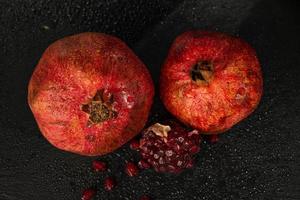 roter reifer nasser Granatapfel auf einem schwarzen Steinbrett foto