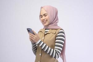 Portrait der schönen Frau mit Hijab mit Handy auf weißem Hintergrund foto