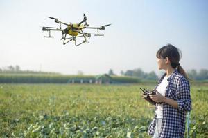 Junger intelligenter Landwirt, der Drohnen kontrolliert, die Düngemittel und Pestizide über Ackerland sprühen, hochtechnologische Innovationen und intelligente Landwirtschaft foto