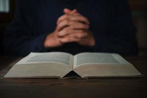 der mann liest und betet die schrift oder die heilige bibel auf einem holztisch mit kopierraum. Religion, Konzept glauben. foto