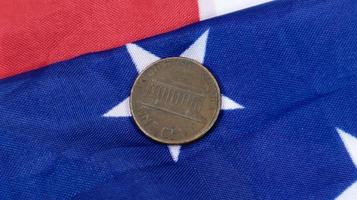 Auf der amerikanischen Flagge liegt eine 1-Cent-Münze des amerikanischen Dollars. die währung ist einen cent über der flagge der vereinigten staaten. foto