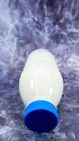 Eine Plastikflasche mit frischer normaler Milch auf einem dunkelgrauen Marmor- oder Betonhintergrund. Nahaufnahme von vorne. weltmilchtag konzept. Nährflüssigkeit. vertikale Fotografie. foto