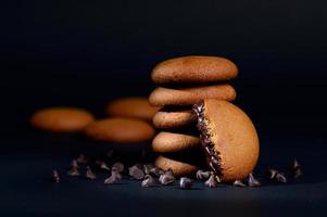 Kekse - Stapel köstlicher Sahnekekse gefüllt mit Schokoladencreme auf schwarzem Hintergrund foto