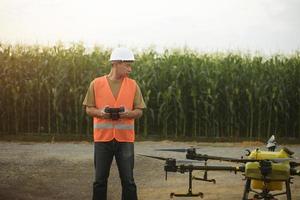 Männlicher Ingenieur, der Drohnen kontrolliert, die Düngemittel und Pestizide über Ackerland sprühen, High-Tech-Innovationen und intelligente Landwirtschaft foto