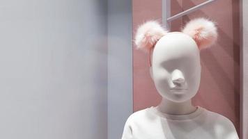 Porträt eines weißen Schaufensterpuppenmädchens auf einem Hintergrund aus hellen, bunten, warmen Rosatönen. kleine Puppe in einem Schaufenster. Boutique mit einer jungen Schaufensterpuppe. Abteilung für Kinderbekleidung. Gesicht ganz nah foto
