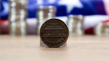 Auf der amerikanischen Flagge liegt eine 1-Cent-Münze des amerikanischen Dollars. die währung ist einen cent über der flagge der vereinigten staaten. foto