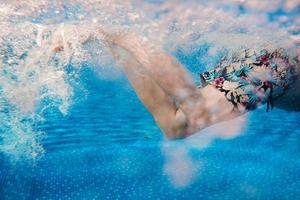 Männerbeine, die im Sommer im Schwimmbad unter Wasser schwimmen foto