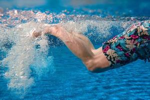 Männerbeine, die im Sommer im Schwimmbad unter Wasser schwimmen foto