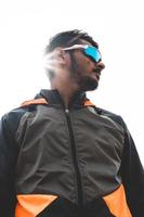 Porträt eines jungen indischen Sportlers, der eine Sport-Sonnenbrille trägt und nach rechts blickt. sport und gesundes lebensstilkonzept. foto