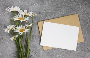 leere weiße Grußkarte und Umschlag mit Kamillenblüten foto