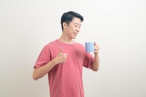 junger asiatischer mann, der kaffeetasse hält foto