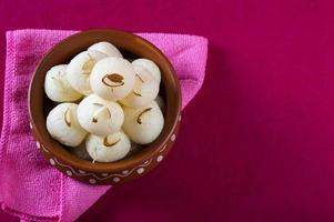 Indische Süßigkeit - Rasgulla, berühmte bengalische Süßigkeit in Tonschale mit Serviette auf rosa Hintergrund pink foto