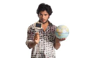 junger Mann mit einer Weltkugel und einem kleinen Brett auf weißem Hintergrund. foto