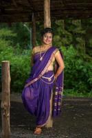 Schönes indisches junges Mädchen im traditionellen Saree posiert im Freien foto