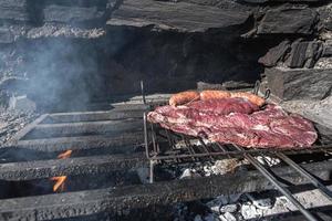 Typisches uruguayisches und argentinisches Asado, das auf Feuer zubereitet wird. Entrana- und Vacio-Fleischstücke. begleitet von Chorizo. foto