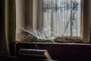 Fensterbank mit alten Vorhängen und Spinnweben in einem Haus foto