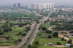 luftlandschaftsansicht einer sich entwickelnden stadt, randbezirke von delhi und gurugram. Luftaufnahme von Feldern und Türmen. foto