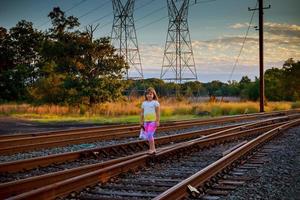 kleines Mädchen mit der Eisenbahn. in der Nähe von Gleisen foto