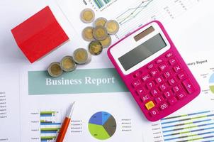 Hypothekendarlehenskonzept mit Taschenrechner und Geldmünze mit rotem Haus auf Geschäftsberichtshintergründen oben foto