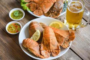 Flathead-Hummergarnelen, serviert auf weißem Teller, Meeresfrüchtesoße und Becherbierglas, frischer Pantoffelhummer-Flathead, gekochtes Kochen mit Petersilie und Rosmarin im Restaurant, Rock-Hummer, Moreton Bay Bug foto