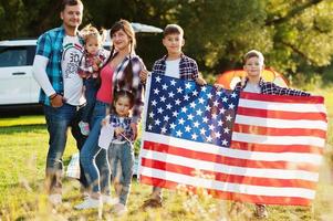 große amerikanische familie, die zeit miteinander verbringt. mit usa-flagge. amerika urlaub. vier Kinder. foto