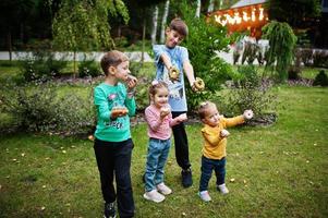 vier kinder mit donuts im abendhof. leckeres leckeres Donut-Essen. foto