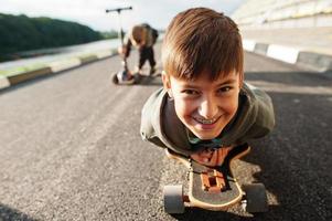 Junge mit geschweiften Klammern auf einem Skateboard liegend, Porträt schließen. foto