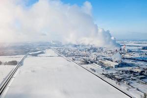 riesige Chemiefabrik auf dem Hintergrund einer schneebedeckten Felddraufsicht. foto