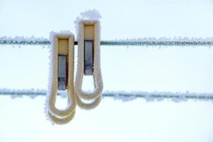 Wäscheklammern im Frost hängen im Winter an einem Seil. Wäscheklammern hautnah. foto