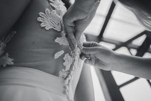 Mama knöpft das Hochzeitskleid der Braut zu foto