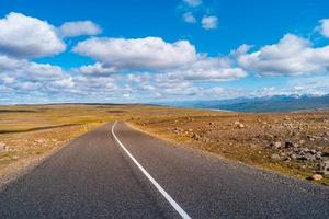 Panoramablick über die Hochlandlandschaft in Island, mit asphaltierter Straße am sonnigen Sommertag und blauem Himmel mit Wolken. foto