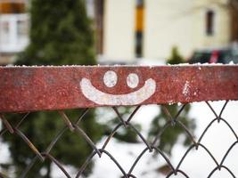 Smiley-Gesicht gezeichnet auf Metallzaun auf Winterhofhintergrund foto