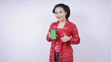 asiatische schönheit in kebaya zeigt smartphone-bildschirmgeste ok isoliert auf weißem hintergrund foto