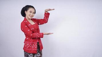 asiatische Schönheit in Kebaya zeigt leere Seite isoliert auf weißem Hintergrund foto