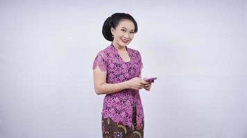 Schönheit in Kebaya spielt mit Handy isoliert auf weißem Hintergrund foto