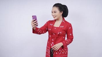 asiatische Schönheit im Kebaya-Selfie auf dem Smartphone isoliert auf weißem Hintergrund foto