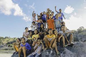 ost nusa tenggara indonesien kinder jubeln zusammen und genießen es, in dem großen felsen am strand zu spielen. ntt rote, indonesien - april 2020. foto