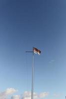 Indonesien-Flagge auf dem Stahlmast auf blauem Himmelshintergrund foto
