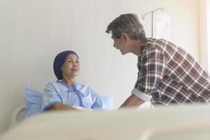 Älterer Mann, der eine krebskranke Frau mit Kopftuch im Krankenhaus, im Gesundheitswesen und im medizinischen Konzept besucht foto