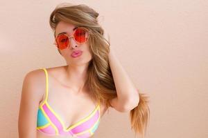 Nahaufnahme eines glücklichen Mädchens mit rosafarbener Sonnenbrille isoliert. Sommerferien und lustiges Wochenende. Sommerkonzept. lächelnde junge Frau im modischen Badeanzug. selektiver Fokus. Strand-Sommer-Outfit. Platz kopieren foto