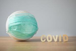 krankenversicherung im coronavirus- oder covid-19-konzept. der ball mit grüner medizinischer maske auf dem tisch. foto