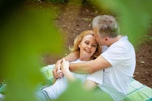 Erwachsenes Paar im Park auf einer Decke umarmt foto