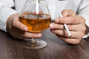 junge Frau, die Alkohol trinkt und in der Bar raucht foto