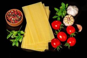 Rohstoffe für Lasagne auf schwarzem Hintergrund foto