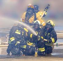 Die Feuerwehrleute mit Schlauch löschen ein Feuer foto