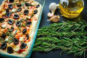 Traditionelle italienische vegetarische Focaccia aus hausgemachtem Brot mit Oliven, Rosmarin foto