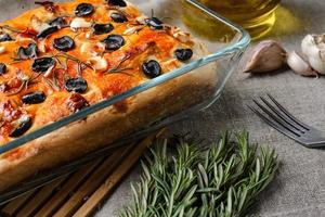 traditionelle italienische vegetarische Focaccia aus hausgemachtem Brot mit Oliven, Rosmarin und Knoblauch foto