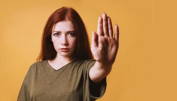 Ernsthafte junge Frau, die mit der linken Hand eine Stoppgeste macht foto