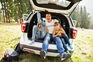 Familie im Fahrzeuginnenraum. Vater mit seinen Söhnen. Kinder im Kofferraum. reisen mit dem auto in den bergen, atmosphärenkonzept. foto