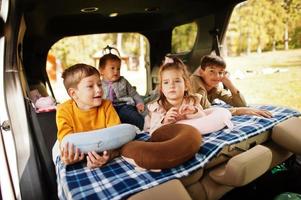 Familie mit vier Kindern im Fahrzeuginnenraum. Kinder im Kofferraum. mit dem auto reisen, liegen und spaß haben, atmosphärenkonzept. foto